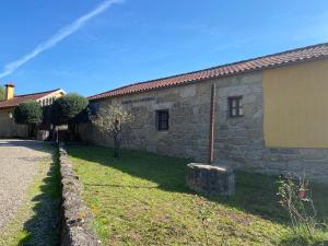 a stone house with a grass yard next to a building at Quinta dos Mouras in Celorico de Basto