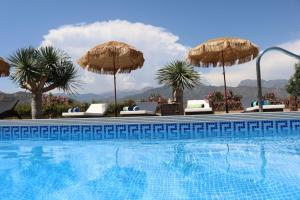 - une piscine avec des parasols et des chaises à côté dans l'établissement Exceptional Costa del Sol villa for 8, Hi spec, Tranquil setting, Amazing views. Heated pool., à Torrox