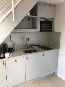 a kitchen with white cabinets and a sink and a staircase at Avanti Apartment Hotel in Stockholm