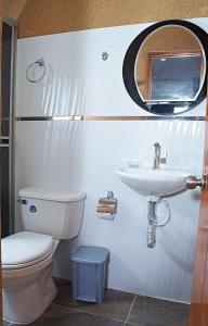 ein Badezimmer mit einem WC, einem Waschbecken und einem Spiegel in der Unterkunft EL CIELO By Ruby in La Victoria