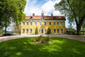 un grand bâtiment jaune avec une pelouse devant lui dans l'établissement Knistad Herrgård, à Skövde