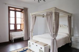 een witte slaapkamer met een hemelbed en een raam bij La Casa Inglesa Vilaflor in Vilaflor