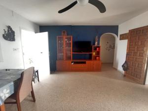 uma sala de estar com uma ventoinha de tecto e uma televisão em The Beach House Denia -- Casa en primera línea de playa - Denia em Denia