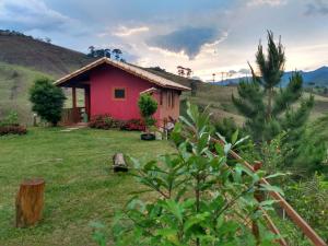 una pequeña casa roja en medio de un campo en Pousada Chales Joao de Barro, en Visconde De Maua