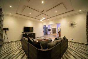 a living room with a large couch and a flat screen tv at The Cabyn in Accra +51 photos