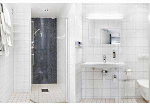 a white bathroom with a shower and a sink at Avanti Apartment Hotel in Stockholm