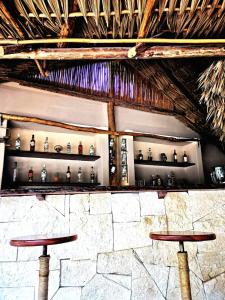 a bar with two stools and shelves of wine bottles at Hotel Circulo Bacalar in Bacalar