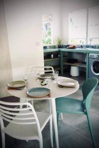 a kitchen with a table and chairs with plates and wine glasses at Cottage « the papaya tree » in Temae