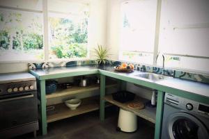a kitchen with green counters and a sink at Cottage « the papaya tree » in Temae