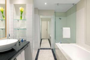 a bathroom with a tub, sink and mirror at Radisson Blu Plaza Hotel Sydney in Sydney