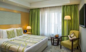 a hotel room with a bed and a chair and a window at Radisson Blu Hotel Ahmedabad in Ahmedabad