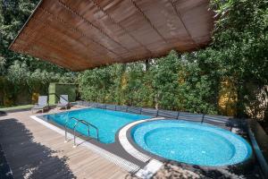 ein Swimmingpool mit Holzdeck und Sonnenschirm in der Unterkunft Radisson Blu Hotel Ahmedabad in Ahmedabad