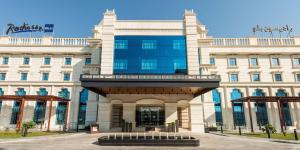 a large white building with a glass facade at Radisson Blu Hotel, Ajman in Ajman 