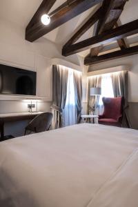 a bedroom with a large white bed and a red chair at Radisson Collection Hotel, Palazzo Nani Venice in Venice