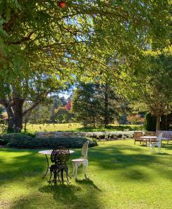 a park with a table and chairs in the grass at Links House in Bowral