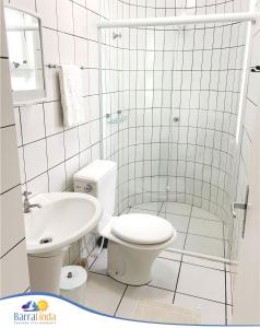 a white bathroom with a toilet and a sink at Pousada Barra Linda in Florianópolis
