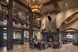 a large lobby with a stone fireplace and a chandelier at Glacier International Lodge in Kalispell
