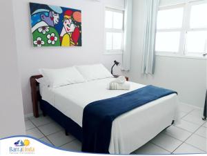 Un dormitorio con una cama blanca y una pintura en la pared en Pousada Barra Linda, en Florianópolis