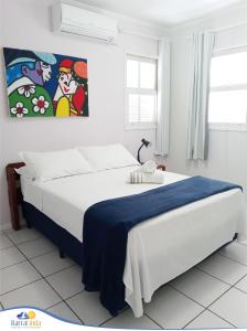 1 dormitorio blanco con 1 cama con manta azul en Pousada Barra Linda, en Florianópolis