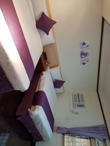 Cette petite chambre comprend un lit avec des oreillers violets et blancs. dans l'établissement Hua Luo Mi No. 35, à Hengchun Old Town