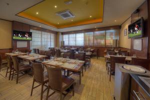 a dining room with tables and chairs and televisions at Fortune Pearl Hotel in Dubai