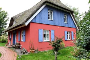 a red and blue house with a thatched roof at Darßer Landhaus in Prerow