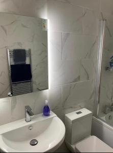 a bathroom with a sink and a toilet and a mirror at Luxury Modern 1Bed Sea View Apartment in Llandrillo-yn-Rhôs