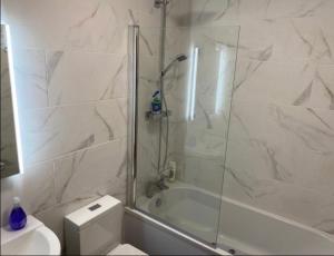 a white bathroom with a shower and a toilet at Luxury Modern 1Bed Sea View Apartment in Llandrillo-yn-Rhôs