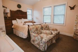 a bedroom with a bed and a couch and a chair at Garden Grove Inn Bed and Breakfast in Union Pier