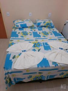 a bed with a blue and white comforter and pillows at POUSADA ROTA DAS ÁGUAS in São Félix do Tocantins
