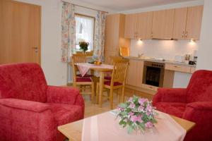ein Wohnzimmer mit roten Stühlen und einem Tisch mit Blumen darauf in der Unterkunft Ferienwohnungen am Westernberg in Ruhpolding