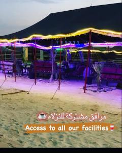 a tent with purple and purple lights on a beach at Royal Tours Permanent Camp in Umm Lajj
