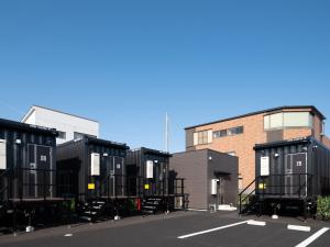 una fila de contenedores de transporte negro en un estacionamiento en HOTEL R9 The Yard Asahishiro en Asahi