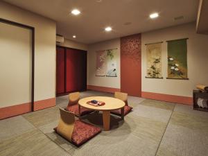 a room with a table and chairs and paintings at Village Kyoto in Kyoto