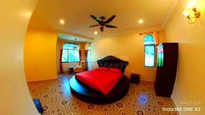 Un dormitorio con una cama roja y un ventilador de techo. en Tuna Cameron Homstay, en Brinchang