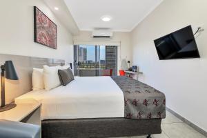 a hotel room with a bed and a television at Argus Hotel Darwin in Darwin