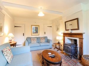a living room with a blue couch and a fireplace at Gardener's Cottage in Hadleigh