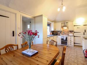 una cocina con una mesa de madera con un jarrón de flores. en Gardener's Cottage en Hadleigh