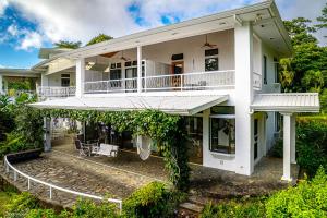 a large white house with a balcony at Villa Corazón - private beach at Lake Arenal in Nuevo Arenal
