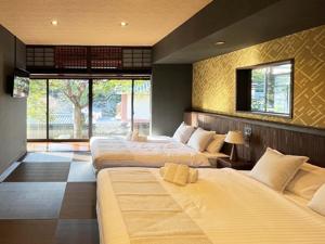 a hotel room with three beds and a window at KIYOMORI in Hatsukaichi