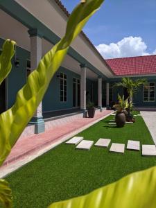 a house with a green lawn in front of it at D'EMBUN INAP DESA BESUT in Kampung Raja