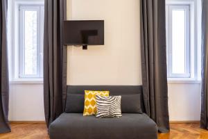 ein Sofa mit zwei Kissen darauf in einem Zimmer mit Fenstern in der Unterkunft Elegante appartamento vicino alla stazione - Gold in Triest