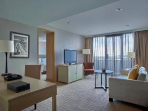 a hotel room with a couch and a television at New World Makati Hotel, Manila in Manila