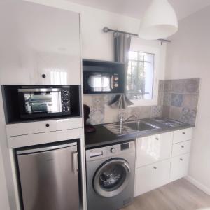 uma cozinha com uma máquina de lavar roupa e um micro-ondas em maison aubenas le lavandin em Ucel