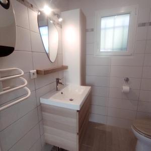 uma casa de banho branca com um lavatório e um espelho em maison aubenas le lavandin em Ucel