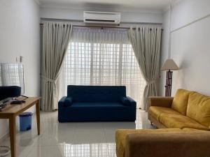 ein Wohnzimmer mit einem blauen Sofa vor einem Fenster in der Unterkunft Norjannah Homestay @Regency Tg Tuan Beach Resort in Port Dickson
