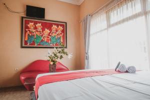 a bedroom with a bed and a red chair and a window at Koolkost Syariah near Plaza Ambarukmo - Minimum Stay 30 Nights in Yogyakarta