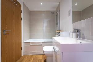 a bathroom with a toilet and a sink and a tub at Blue Haven Silver Service Apartments Free Parking in Southampton
