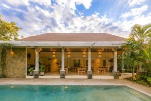 a house with a swimming pool in front of it at La Berceuse Resort and Villa Nusa Dua by Taritiya Collection in Nusa Dua
