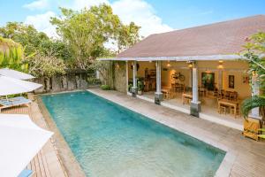 a house with a swimming pool in front of a house at La Berceuse Resort and Villa Nusa Dua by Taritiya Collection in Nusa Dua